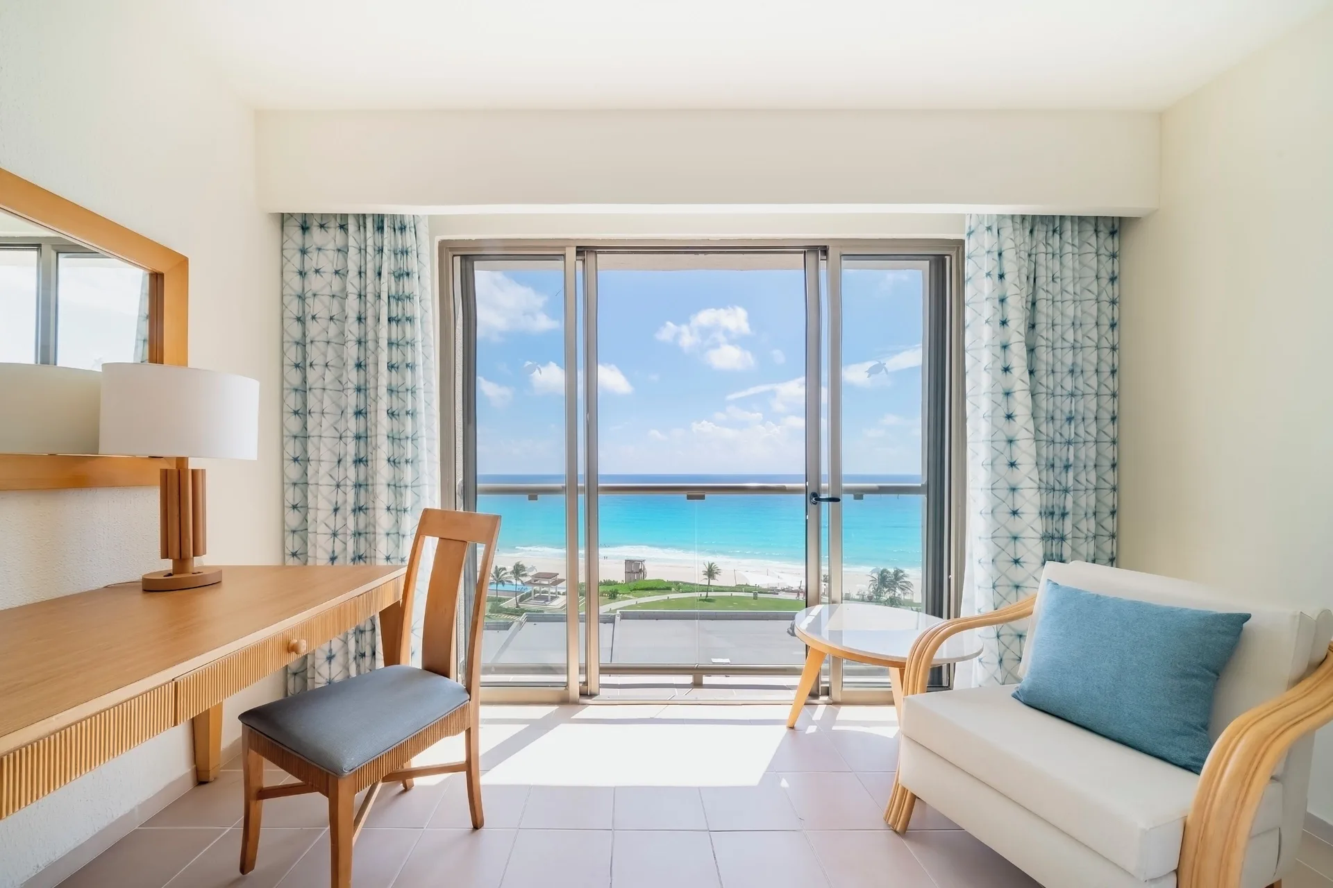 Standard Room sitting area with desk, armchair, balcony doors, and ocean view at Iberostar Selection Cancún.