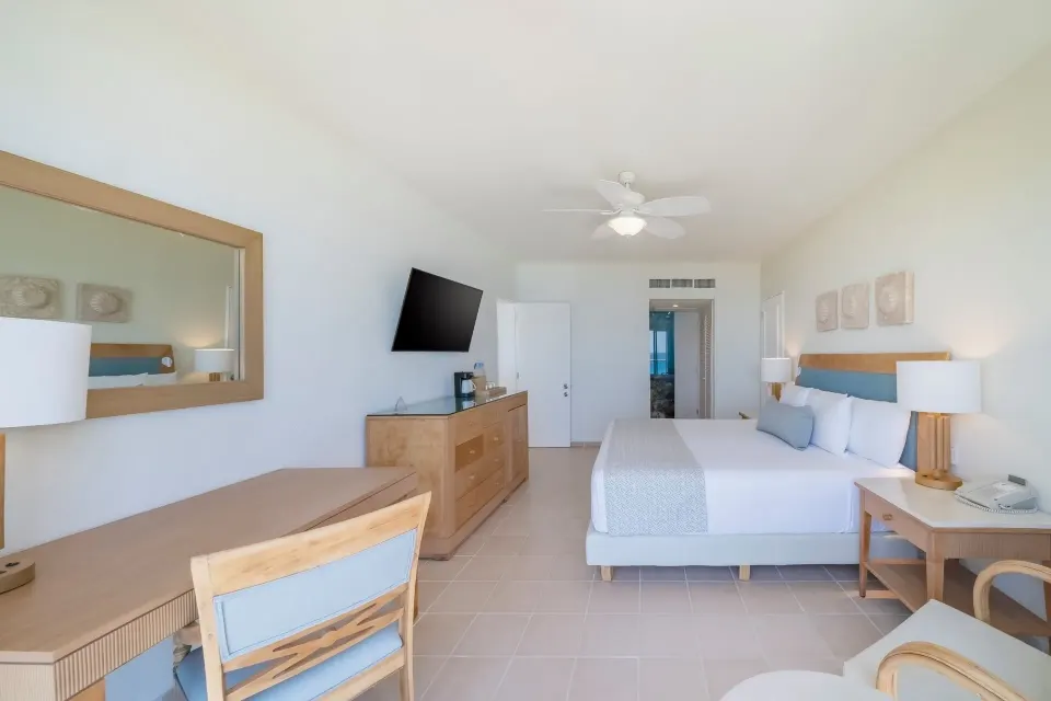 Suite Ocean View bedroom with king bed, desk, dresser and TV at Iberostar Selection Cancún.