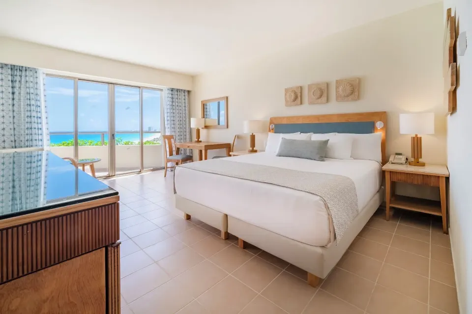 Oceanfront suite king bed facing balcony doors at Iberostar Selection Cancún.
