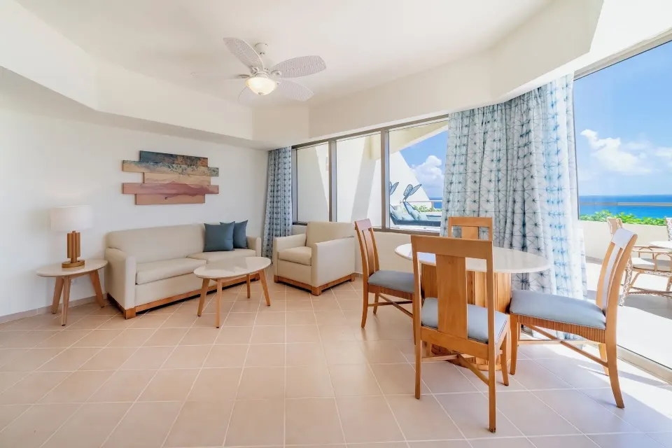 Oceanfront suite living room with sofa and dining table at Iberostar Selection Cancún.