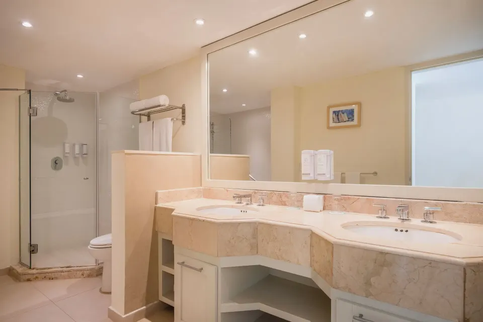 Villa oceanfront bathroom with double vanity and glass shower at Iberostar Selection Cancún.