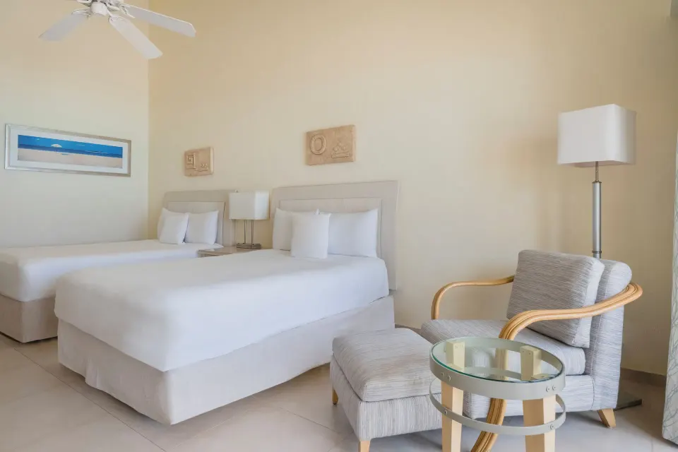 Villa oceanfront room seating area and two beds at Iberostar Selection Cancún.