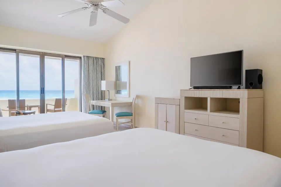Villa oceanfront room with two beds, TV cabinet, and balcony at Iberostar Selection Cancún.