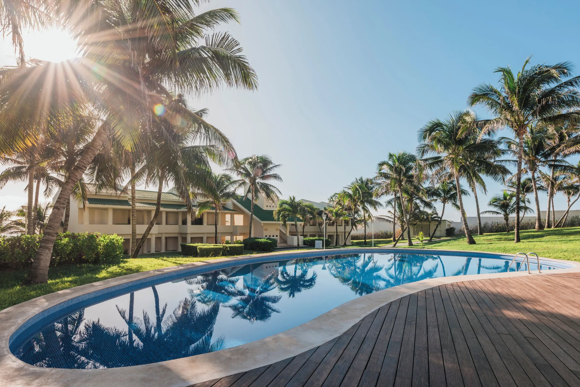 Villa Poolside area with pool, palms, and villas at Iberostar Selection Cancún.