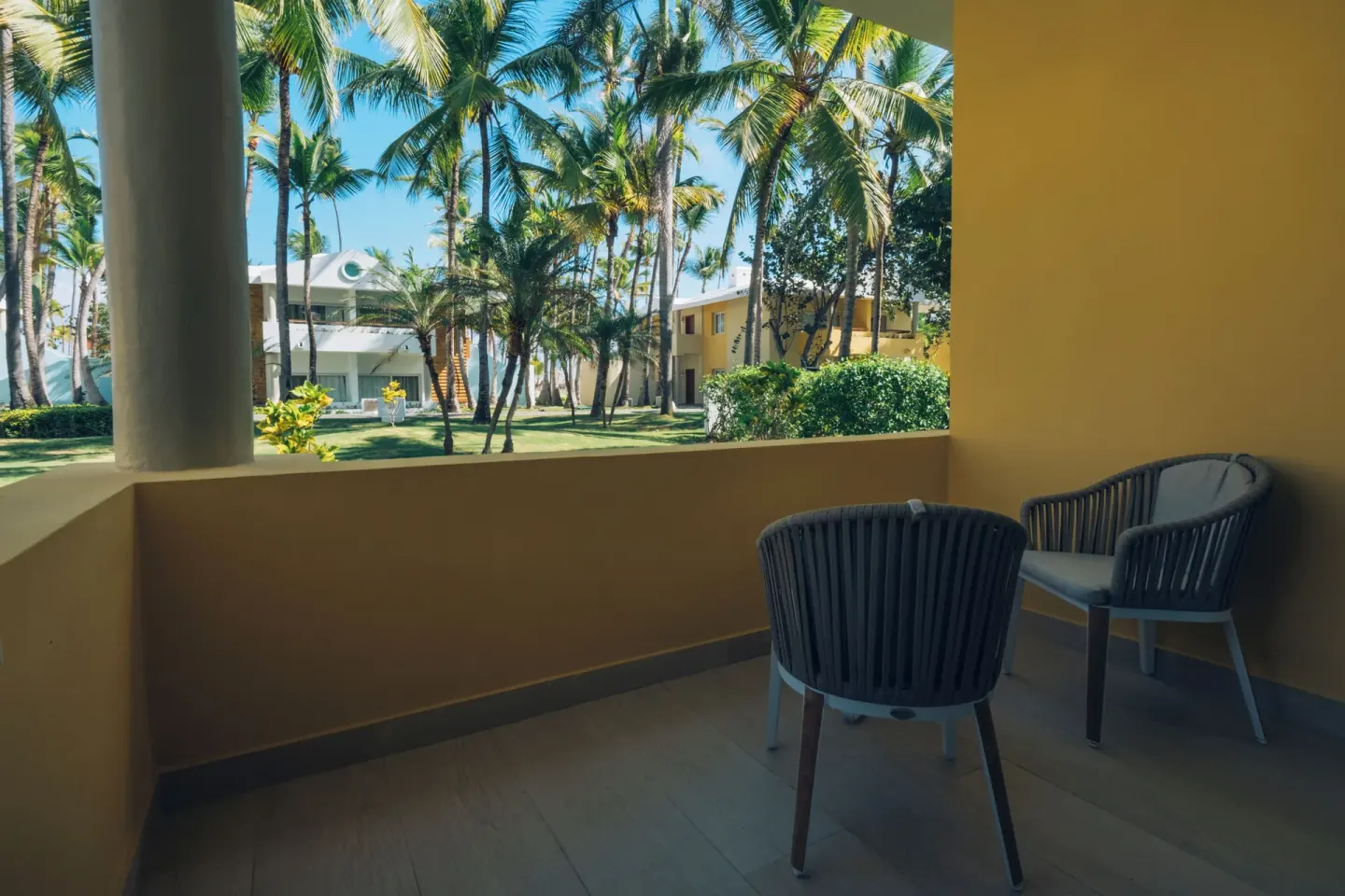 Covered terrace with chairs overlooking palms and gardens at Iberostar Selection Coral Bávaro.