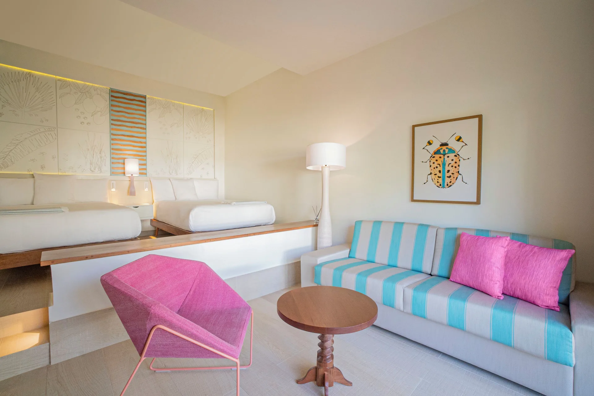 Guest room sitting area with two beds and colorful sofa at Iberostar Selection Coral Bávaro.