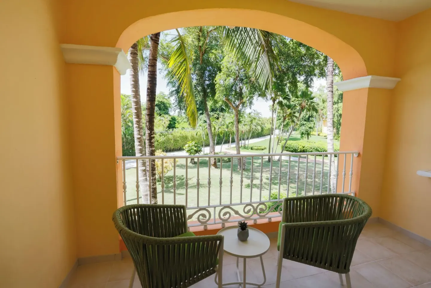Arched balcony with two chairs overlooking gardens at Iberostar Selection Hacienda Dominicus.