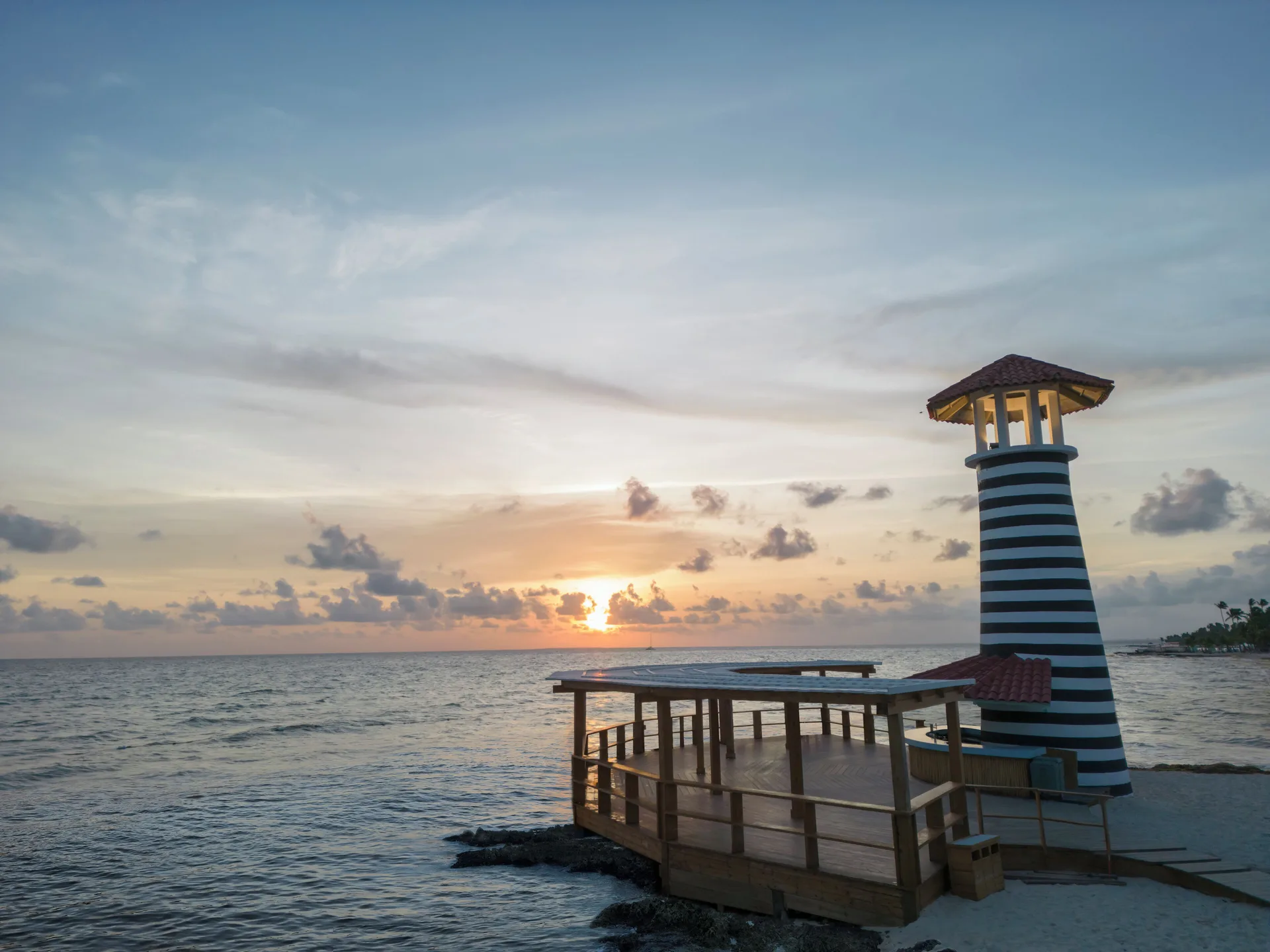 Striped lighthouse by the sea at sunset at Iberostar Selection Hacienda Dominicus.