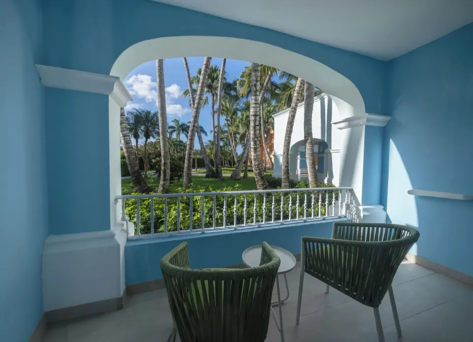 Blue arched balcony with chairs and garden view at Iberostar Selection Hacienda Dominicus.