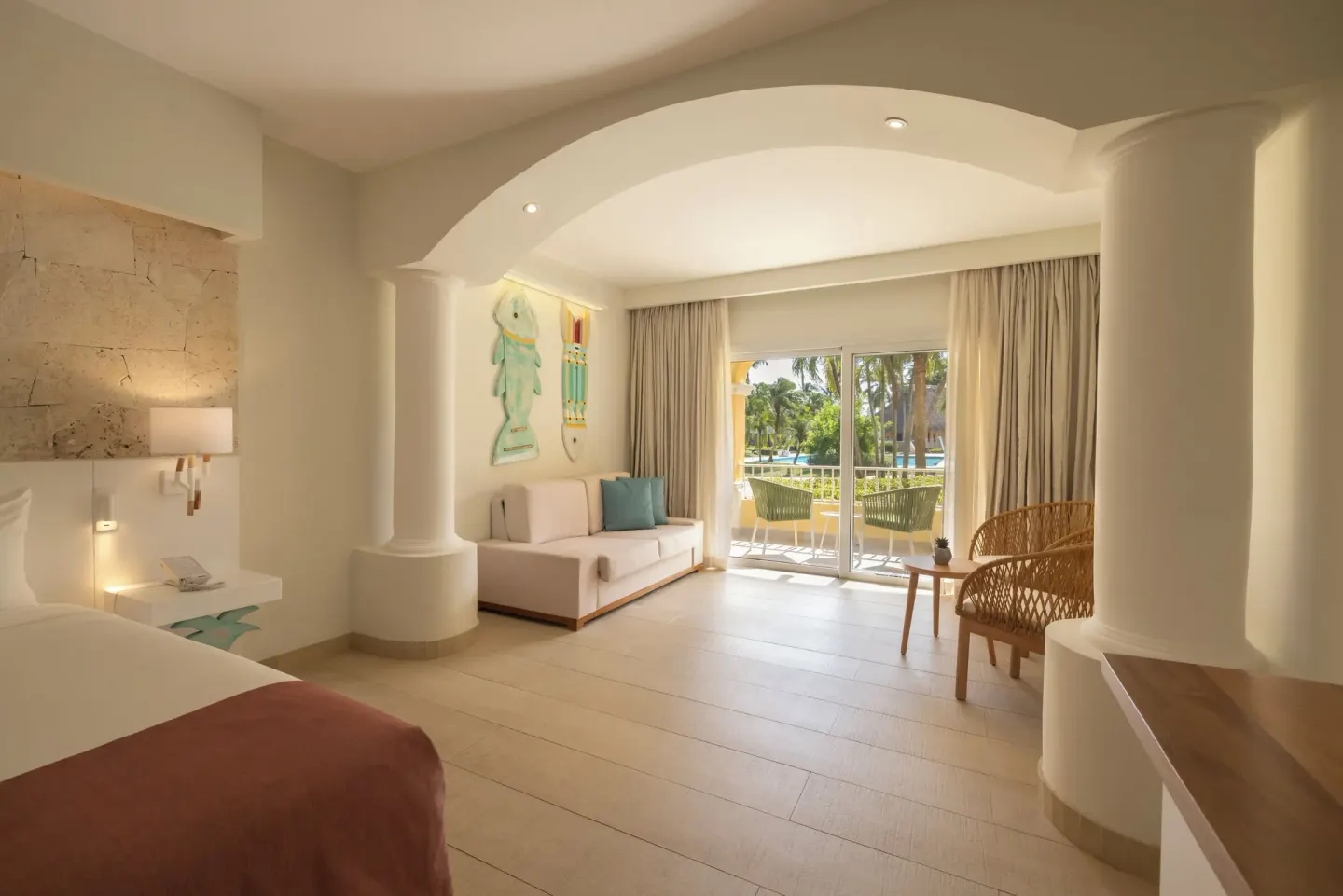 Guest room sitting area and balcony by a king bed at Iberostar Selection Hacienda Dominicus.