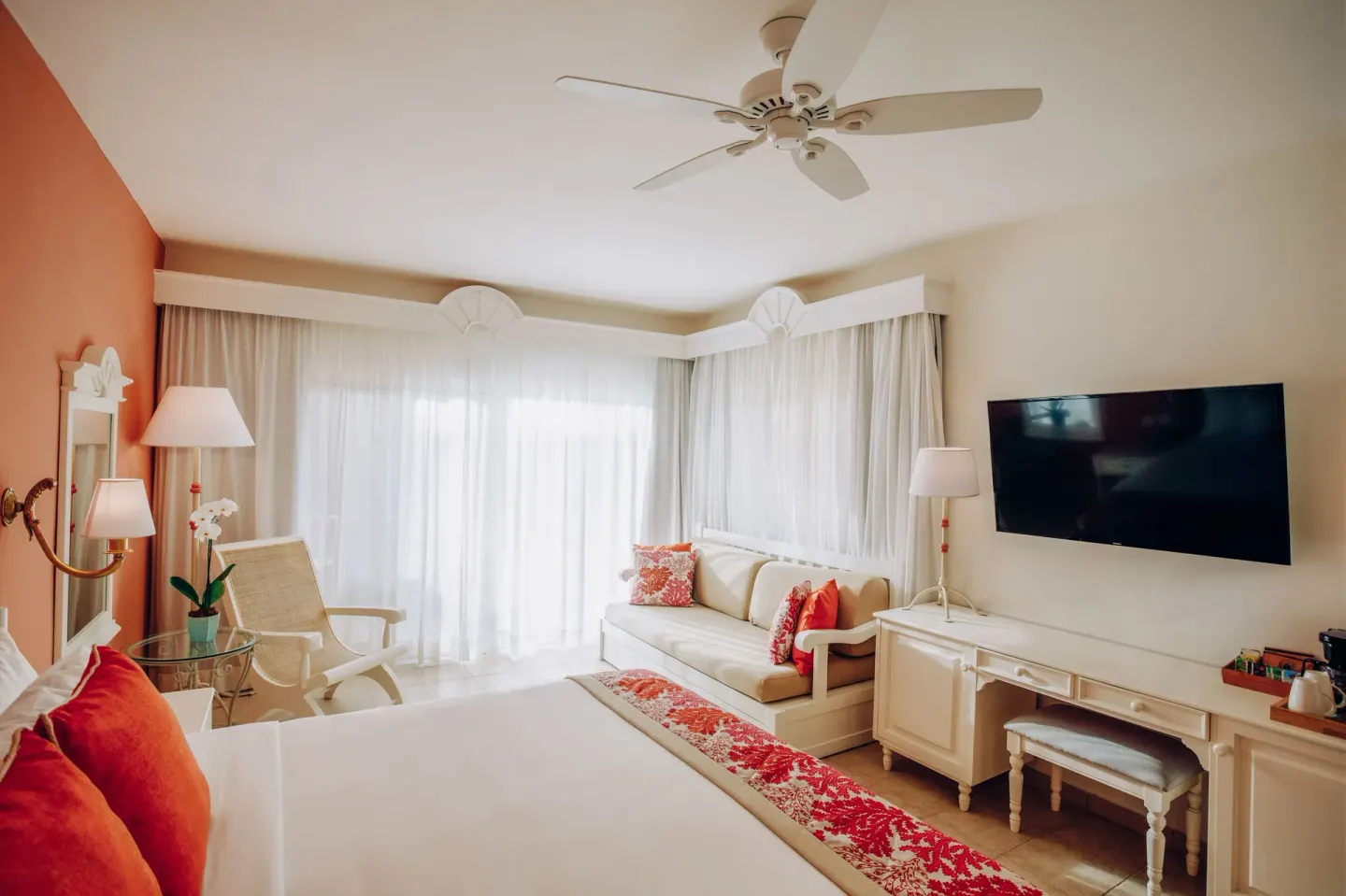 Guest room with king bed, sofa, and wall-mounted TV at Iberostar Selection Hacienda Dominicus.