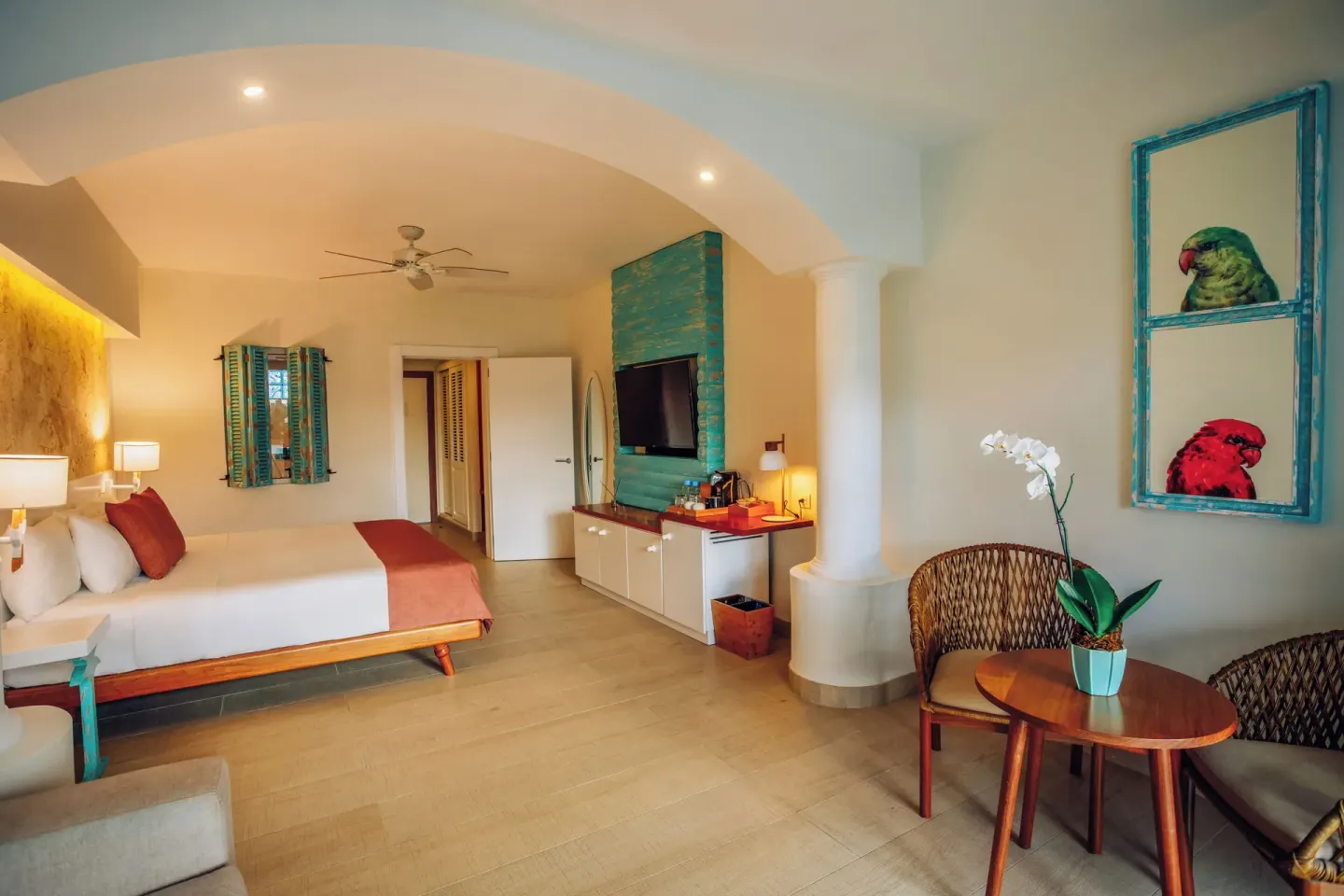 Guest room with king bed, TV wall and wicker seating at Iberostar Selection Hacienda Dominicus.