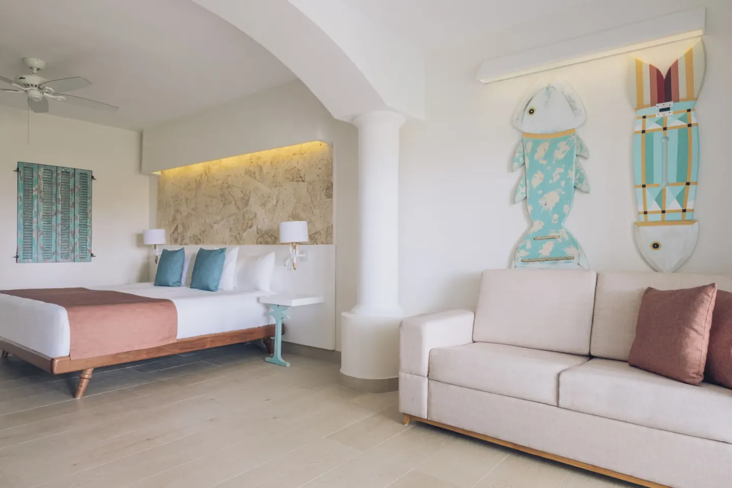 Junior suite with king bed and sofa under fish wall art at Iberostar Selection Hacienda Dominicus.