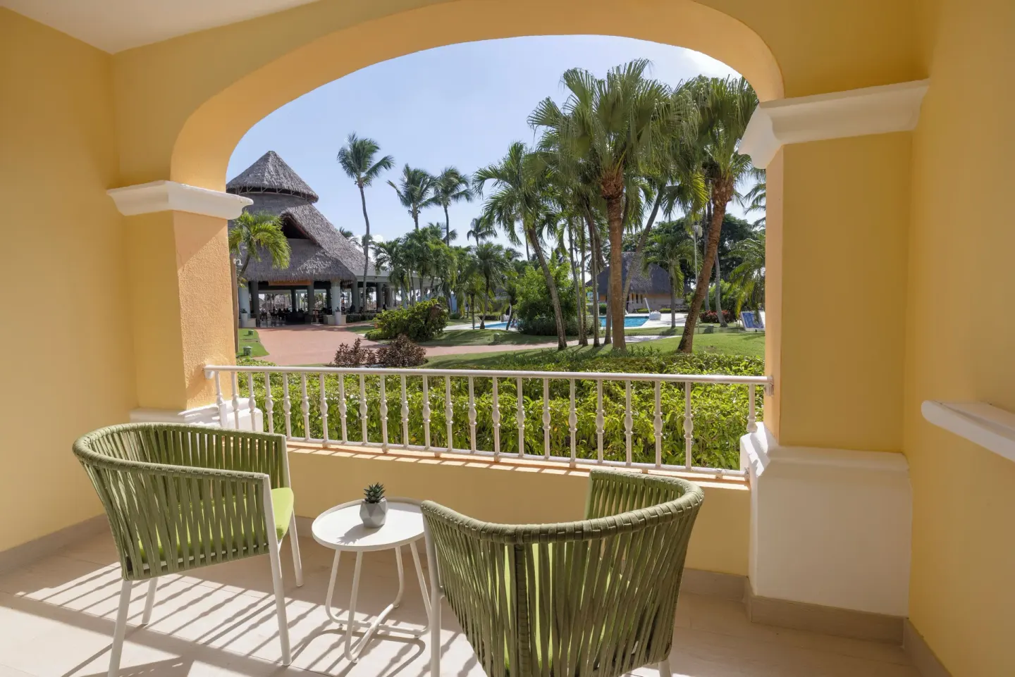 Yellow balcony with chairs overlooking palms at Iberostar Selection Hacienda Dominicus.