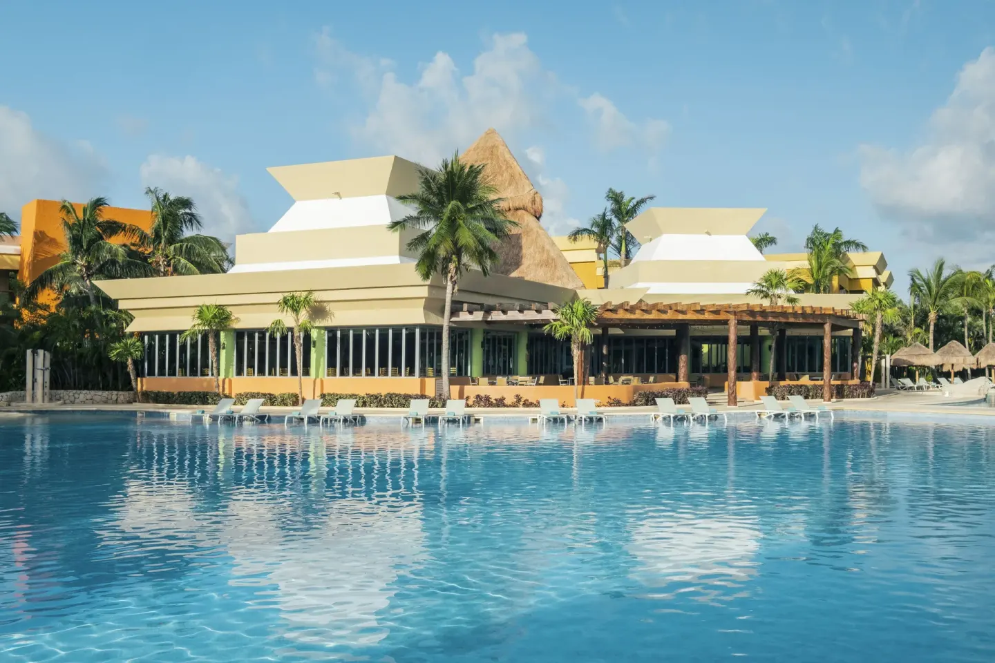 Main pool with loungers and palm-lined resort buildings at Iberostar Selection Paraíso Lindo.