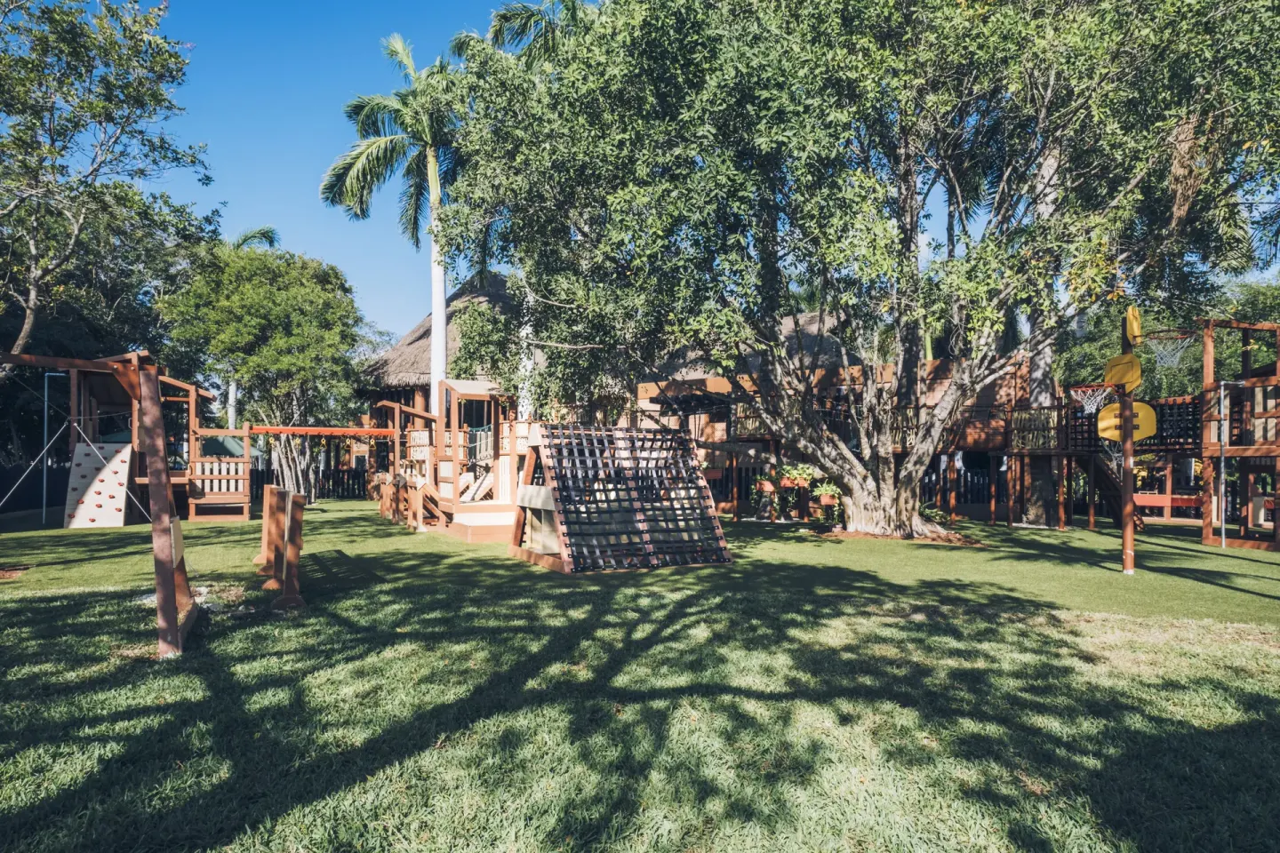 An outdoor playground under large trees at Iberostar Selection Paraíso Lindo.