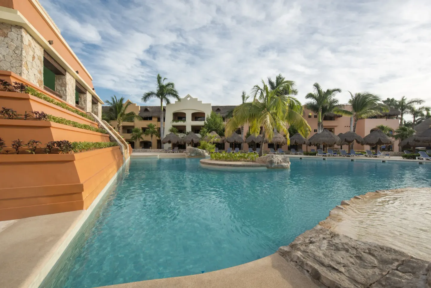 Resort pool with palms, palapas, and guest buildings at Iberostar Selection Paraíso Lindo.