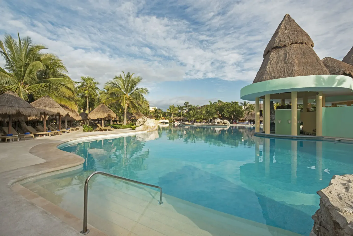 Curving resort pool with palapas and palms at Iberostar Selection Paraíso Lindo.