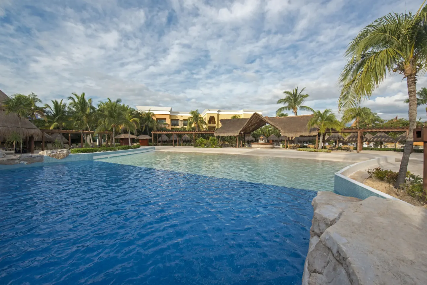 Wide pool area with shallow section and thatched roofs at Iberostar Selection Paraíso Lindo.