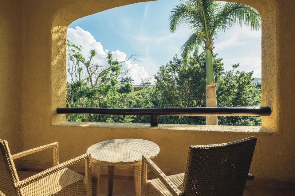 Premium Room balcony with wicker seating and tropical trees at Iberostar Selection Paraíso Lindo.