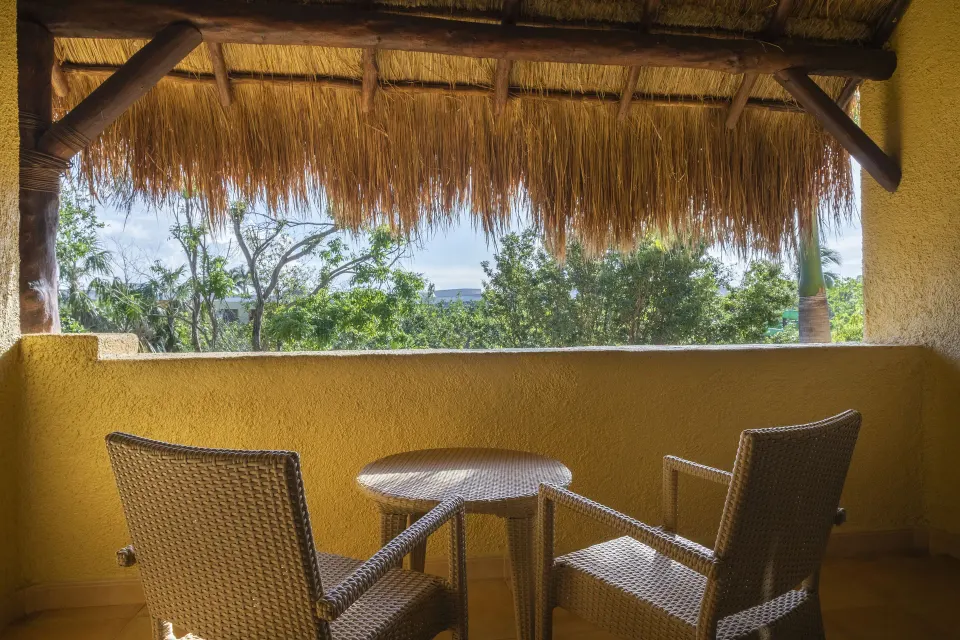 Premium Room covered balcony with wicker chairs at Iberostar Selection Paraíso Lindo.