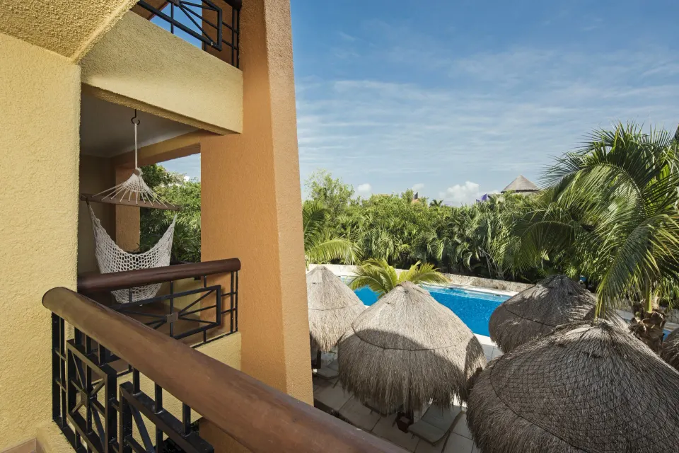 Balcony hammock overlooking palms and pool at Iberostar Selection Paraíso Maya Suites.