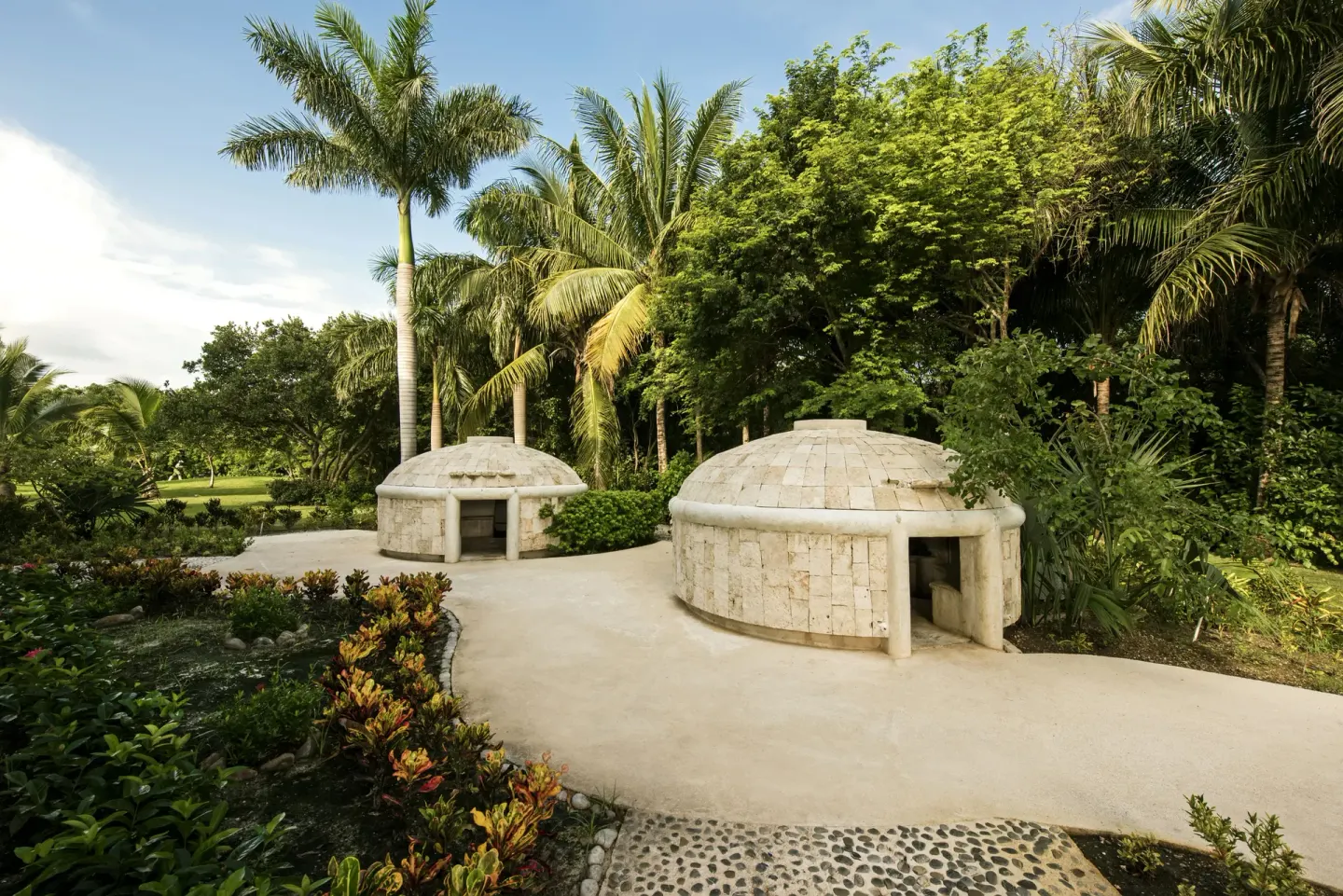 Garden path with small stone hut structures at Iberostar Selection Paraíso Maya Suites.