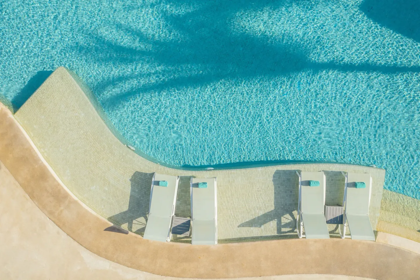 Aerial view of in-water loungers beside a clear pool at Iberostar Selection Paraíso Maya Suites.