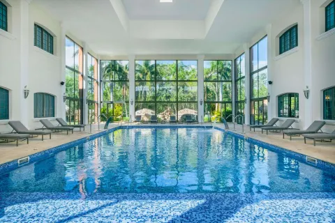 Indoor pool with lounge chairs and tall windows at Iberostar Selection Paraíso Maya Suites.
