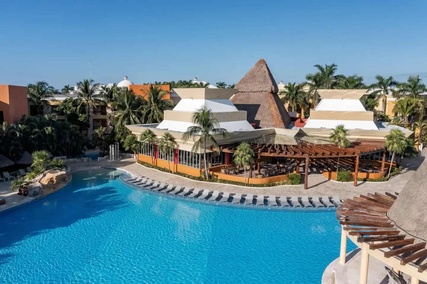 Large resort pool with loungers and palapa roof at Iberostar Selection Paraíso Maya Suites.