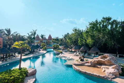 Long pool channel with palapas and rock features at Iberostar Selection Paraíso Maya Suites.