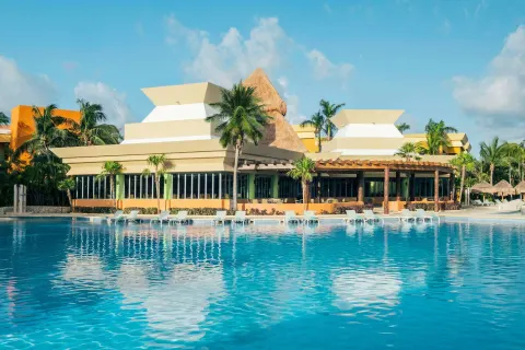 Poolside building and loungers reflected in the water at Iberostar Selection Paraíso Maya Suites.