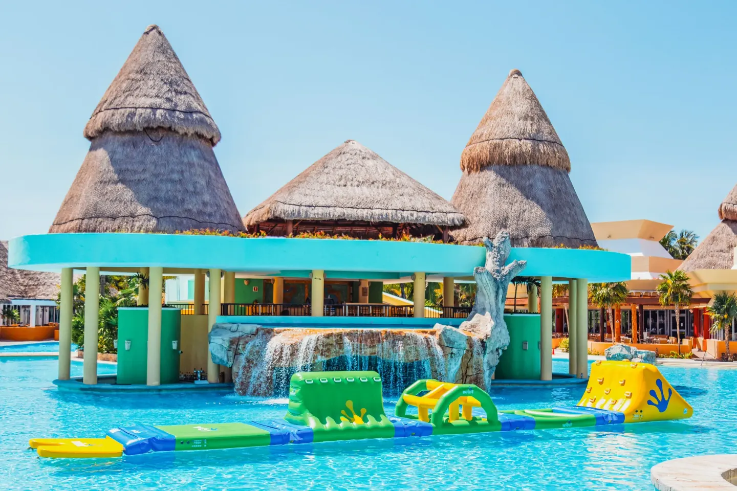 Poolside palapa building with floating obstacle features at Iberostar Selection Paraíso Maya Suites.