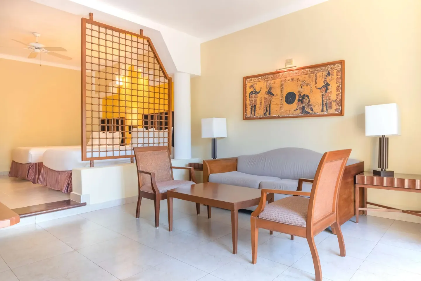 Junior Suite seating area and twin beds beyond a lattice screen at Iberostar Selection Paraíso Maya Suites.