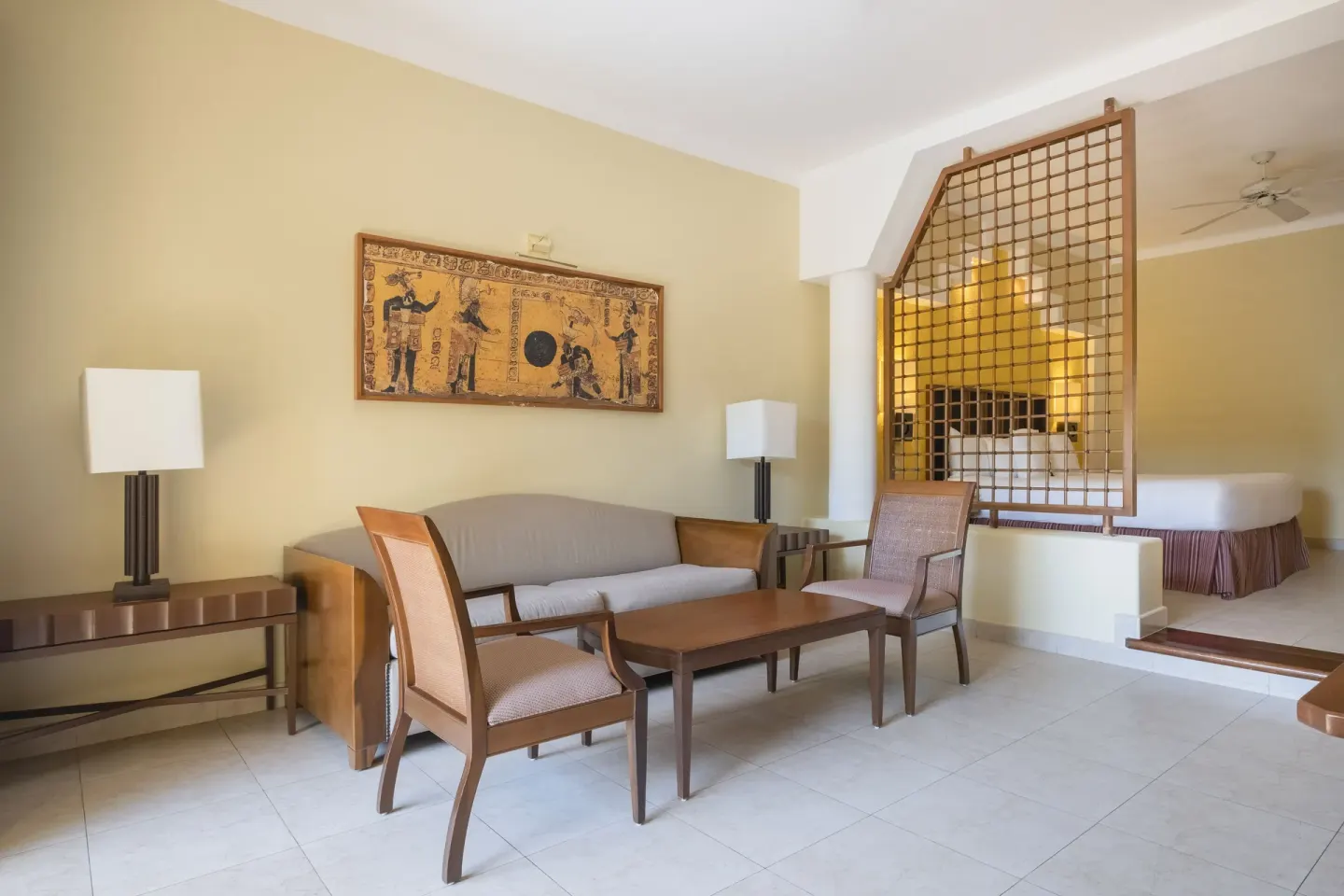 Junior Suite lounge with sofa, chairs, and raised bedroom at Iberostar Selection Paraíso Maya Suites.