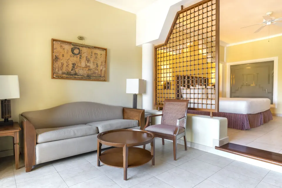 Junior Suite sitting area with sofa and bedroom divider at Iberostar Selection Paraíso Maya Suites.
