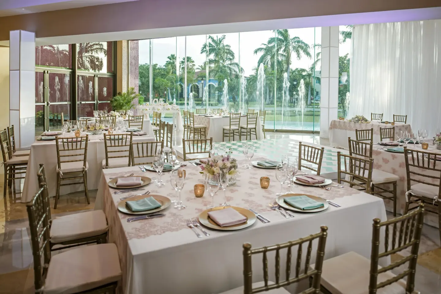 Wedding reception tables by tall windows at Iberostar Selection Paraíso Maya Suites.