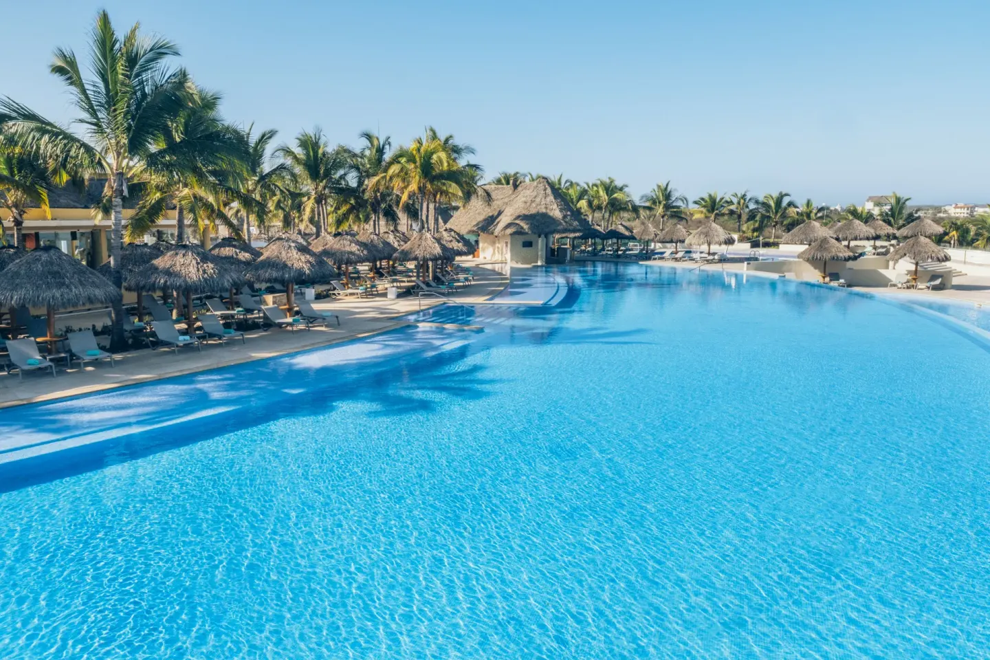 Large resort pool with palapas and palm trees at Iberostar Selection Playa Mita.