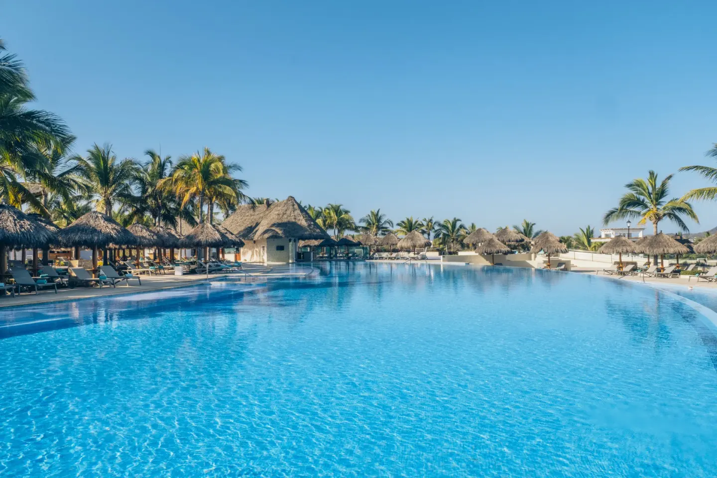 Main resort pool with thatched shade palapas at Iberostar Selection Playa Mita.