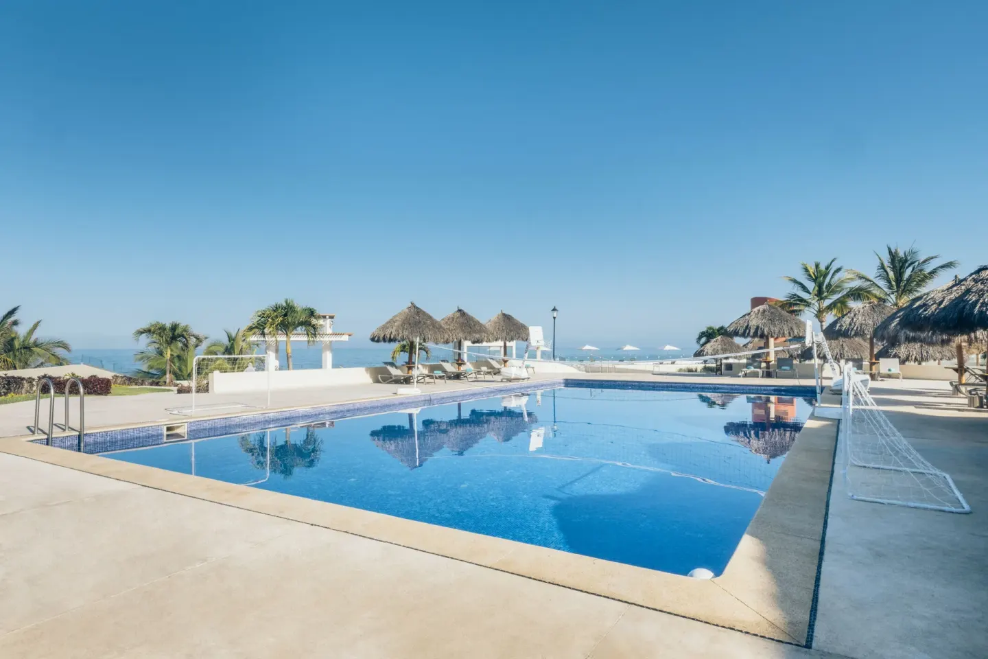Recreation pool with volleyball net and ocean backdrop at Iberostar Selection Playa Mita.