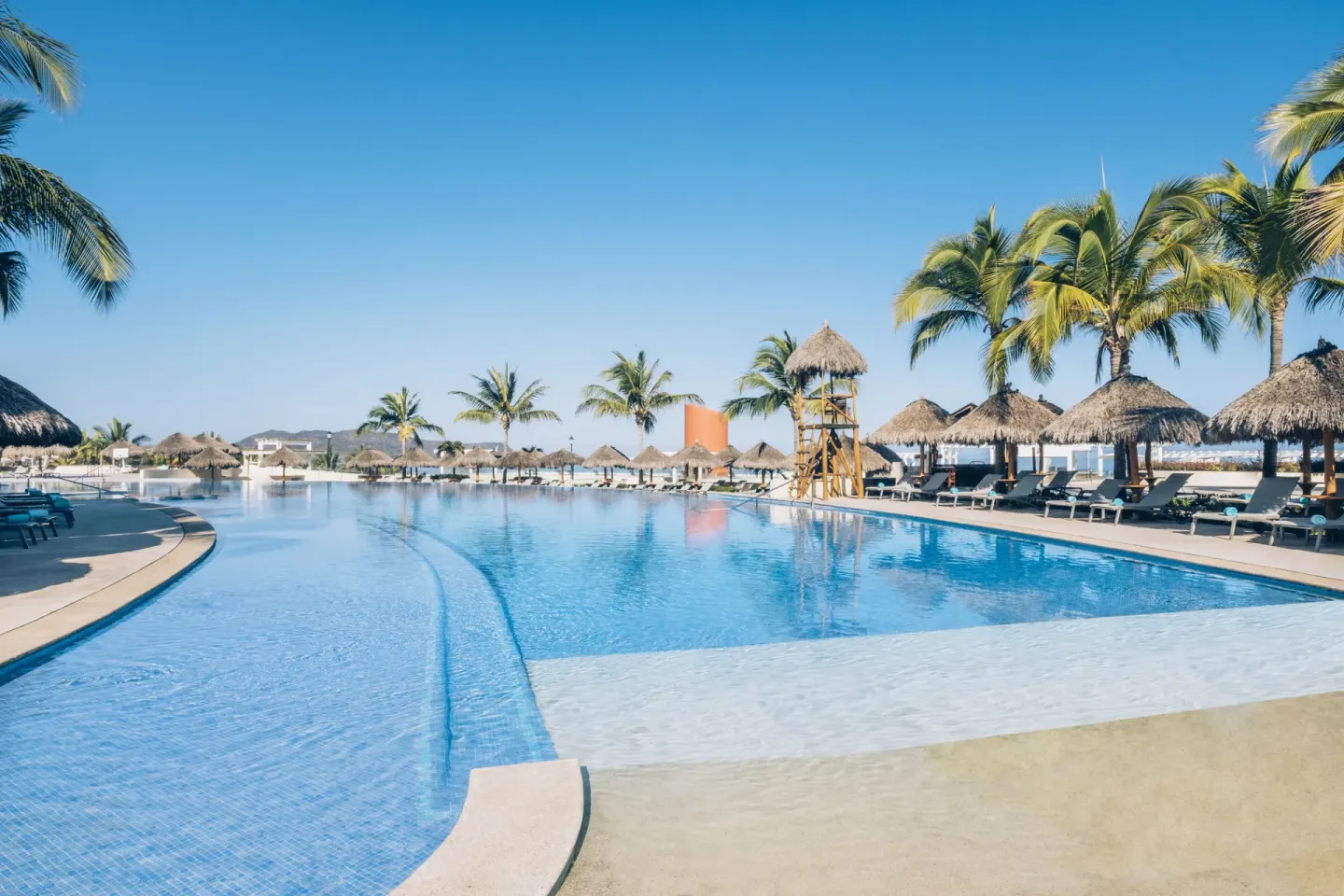 Resort pool with palm trees, loungers, and palapas at Iberostar Selection Playa Mita.