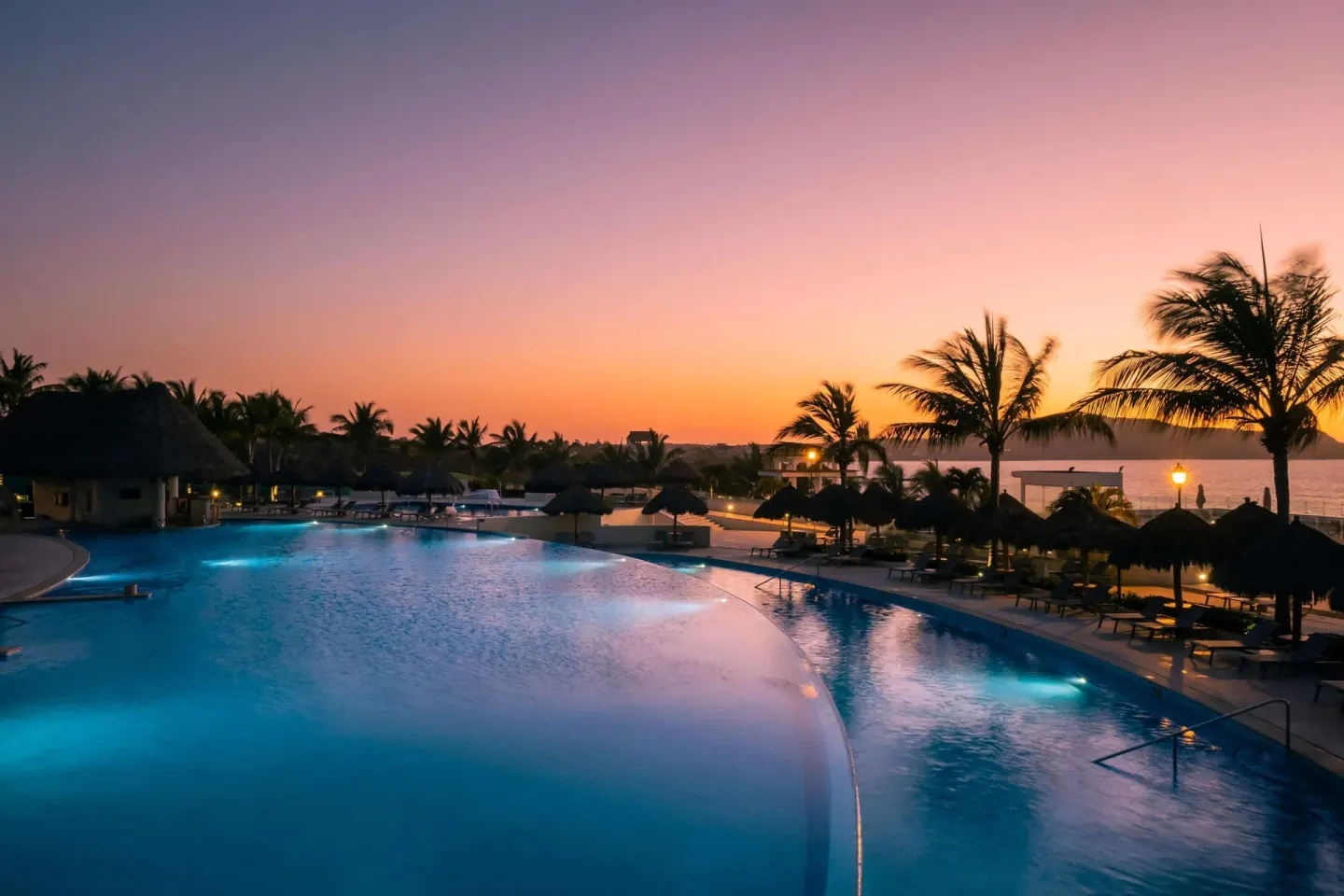 Sunset over the illuminated pool and palms at Iberostar Selection Playa Mita.