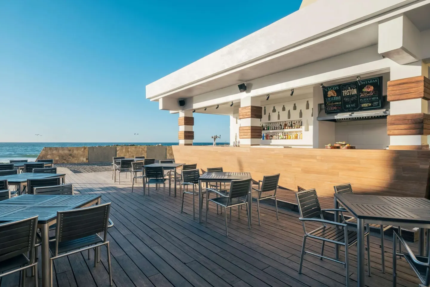 Oceanfront deck bar with tables and menu boards at Iberostar Selection Playa Mita.