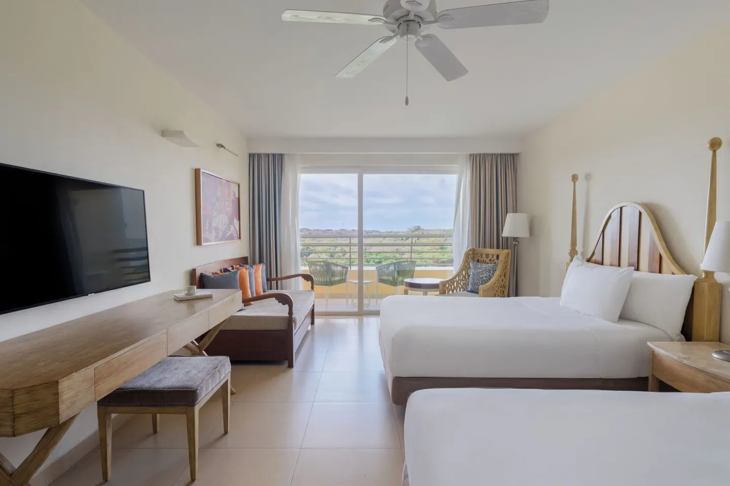 Junior suite with two beds, sofa, TV, and balcony at Iberostar Selection Playa Mita.
