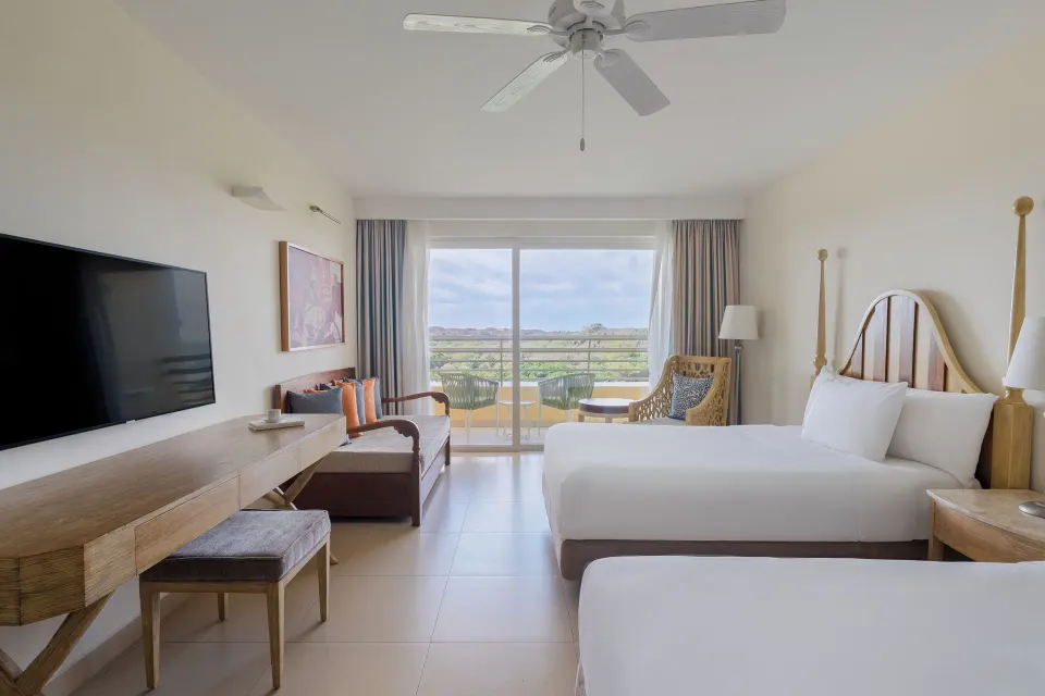 Junior suite with two beds, sofa, TV, and balcony at Iberostar Selection Playa Mita.