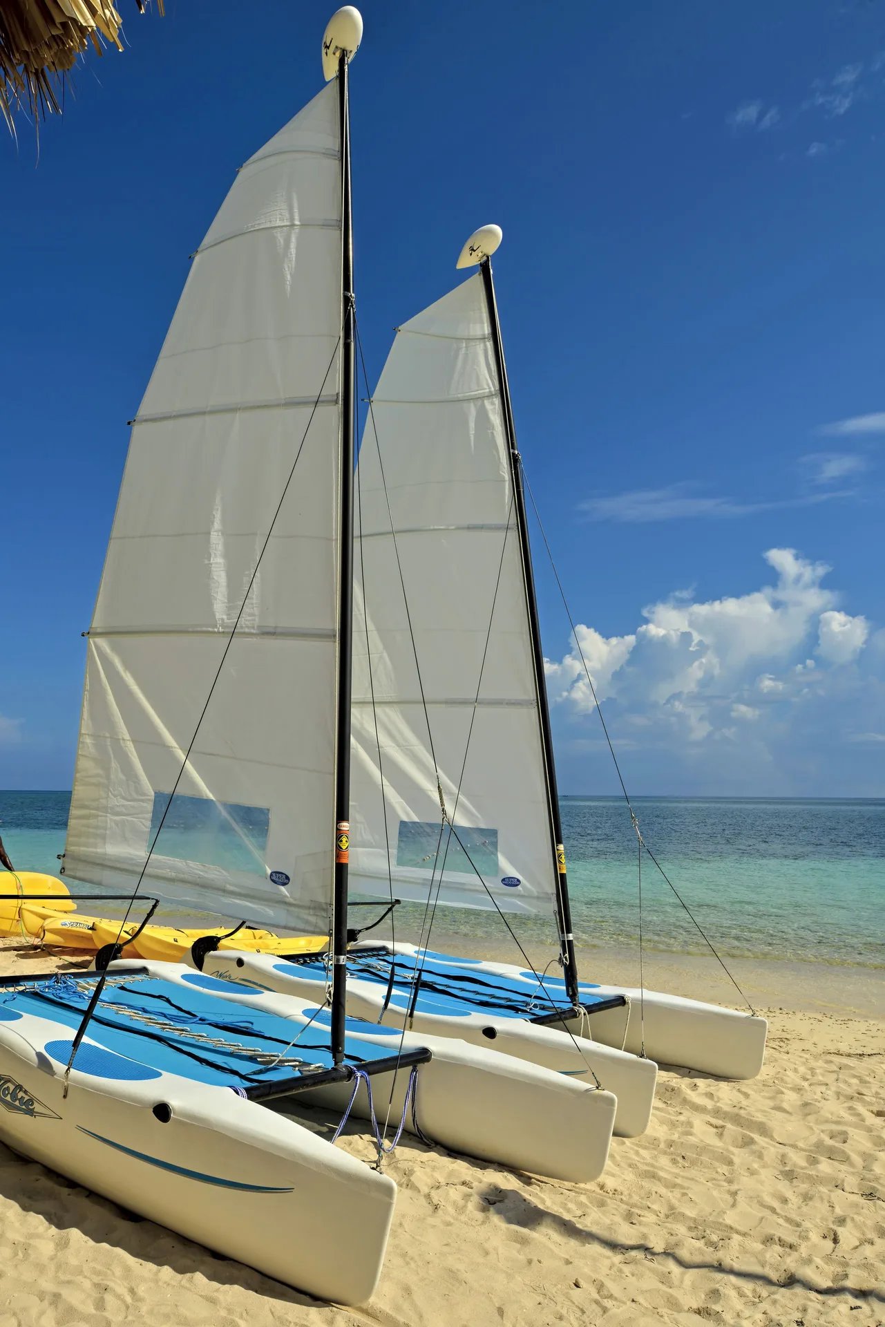 Catamarans with white sails on the beach at Iberostar Selection Rose Hall Suites.