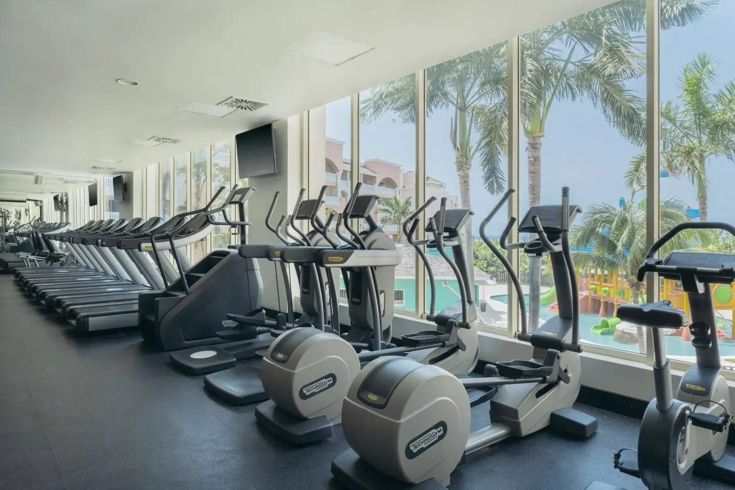 Cardio machines beside tall windows at Iberostar Selection Rose Hall Suites.