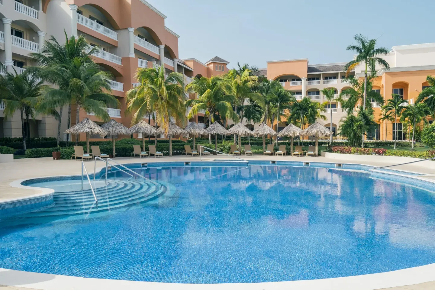 Courtyard pool with palms and resort buildings at Iberostar Selection Rose Hall Suites.