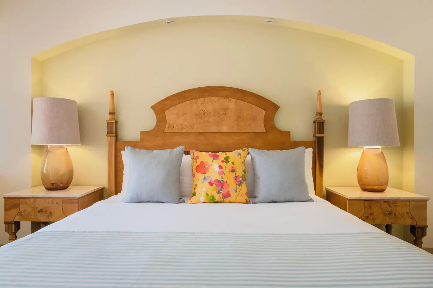 King bed with lamps and colorful pillows at Iberostar Selection Rose Hall Suites.