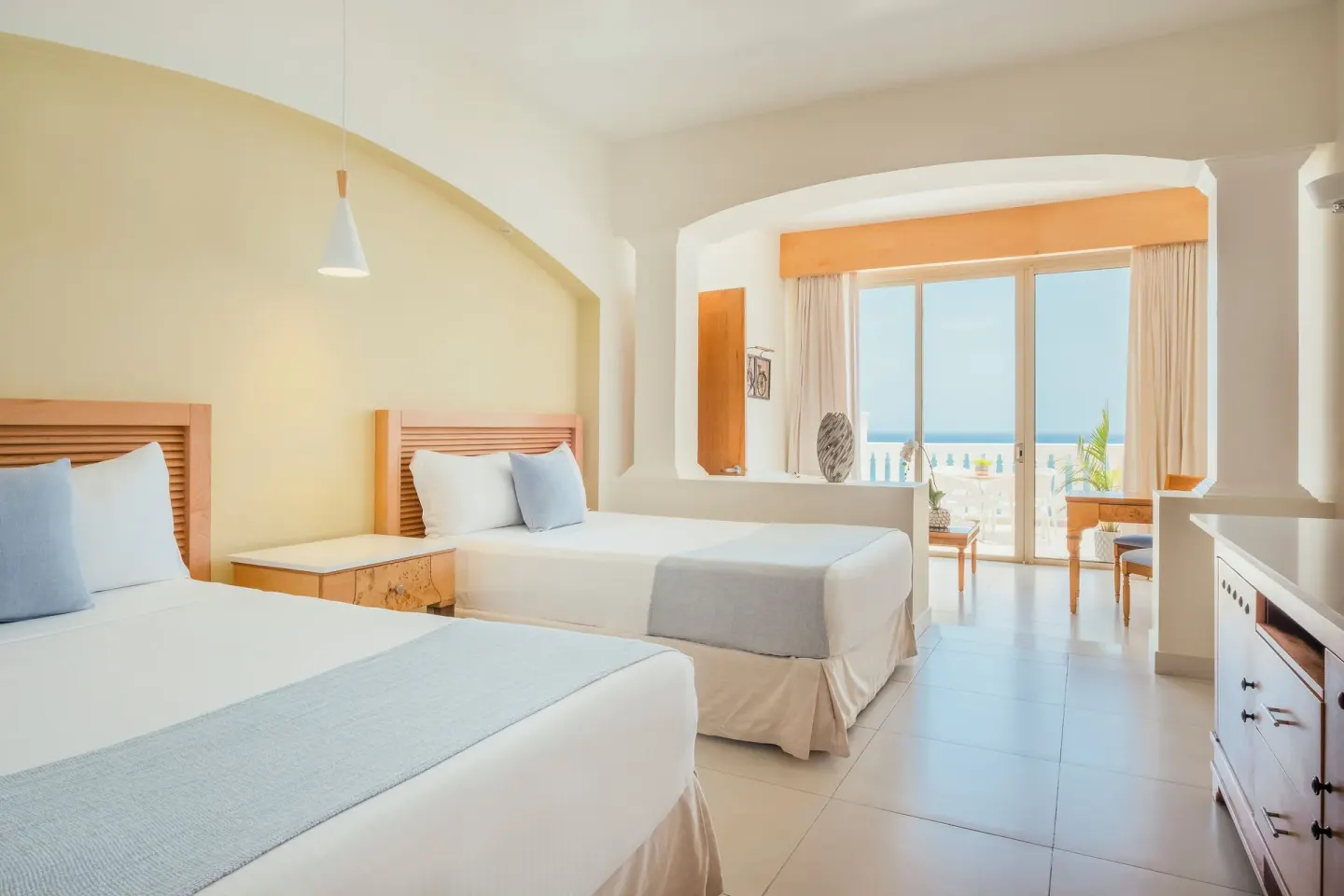 Two-bed guest room with ocean-facing balcony at Iberostar Selection Rose Hall Suites.